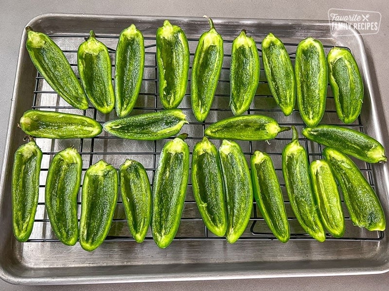 Jalapeno poppers sliced in half and on a baking sheet.