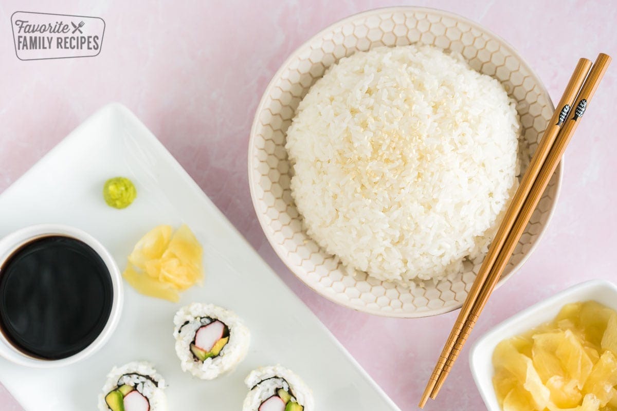 Sushi rice in a bowl next to a plate of California Rolls