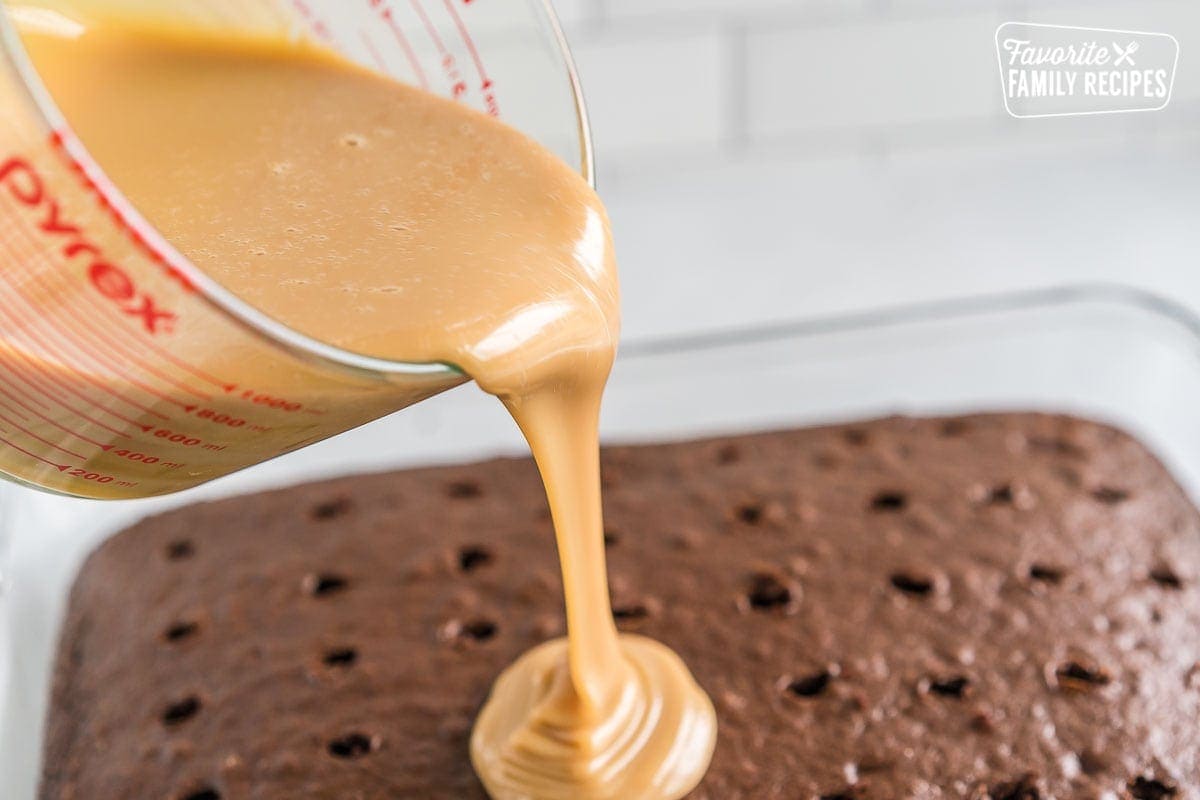 Caramel sauce being poured over chocolate cake