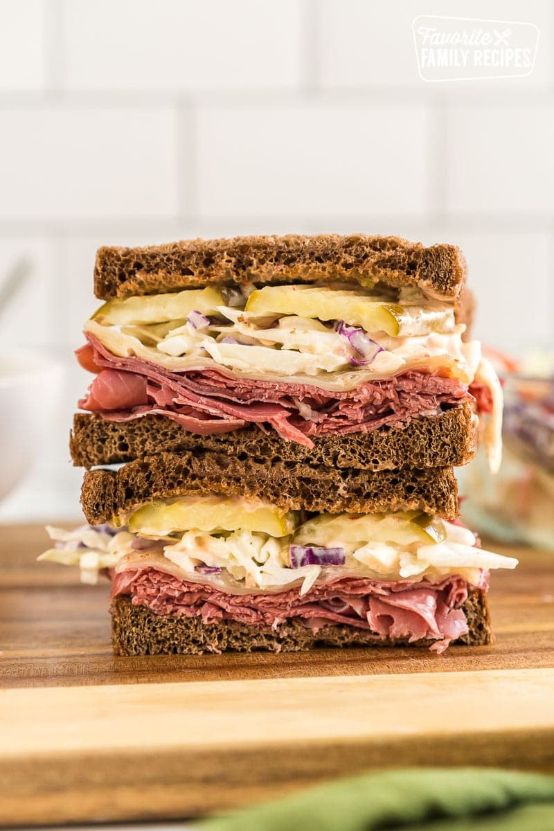 A corned beef sandwich cut in half and stacked one half on top of the other.