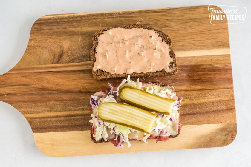 One piece of rye bread spread with Russian dressing and one piece of rye bread with corned beef, melted cheese, coleslaw, and pickles.