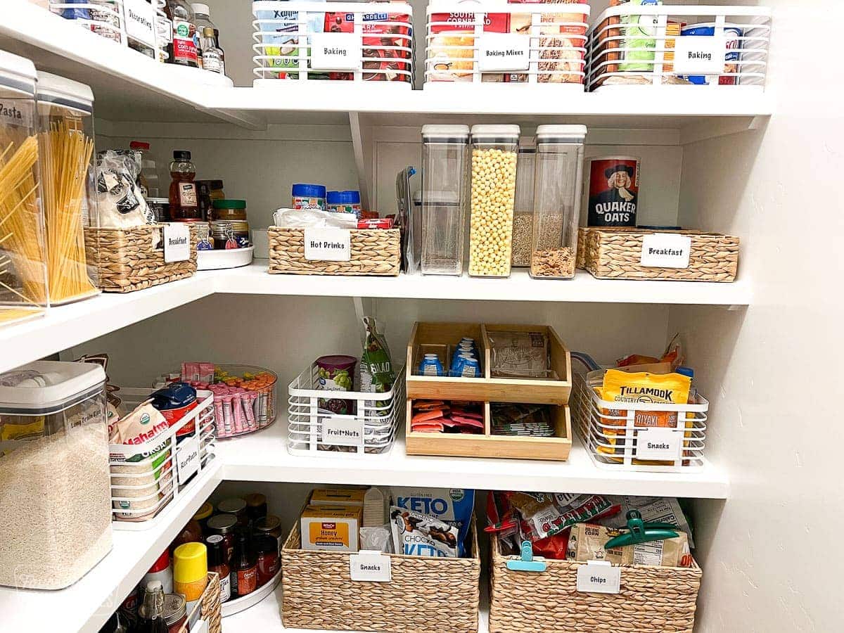 A close up of an organized pantry with items in bins and baskets