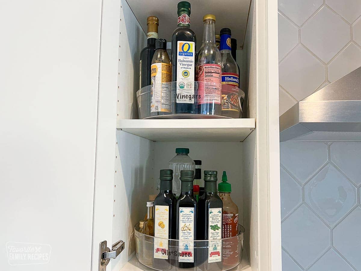 Vinegars, oils, and sauces in a plastic lazy Susan turntable and placed in a cupboard