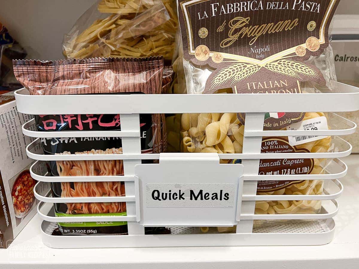 Quick meals such as pasta contained in a bin in a pantry with a label