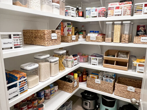 An organized kitchen pantry with bins and containers that are labeled identifying each ingredient