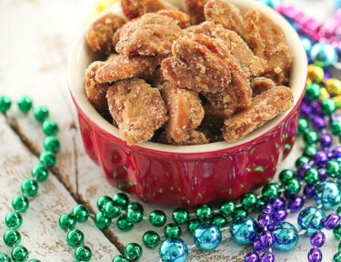 A bowl of pecan pralines with colorful Mardi Gras beads on the side