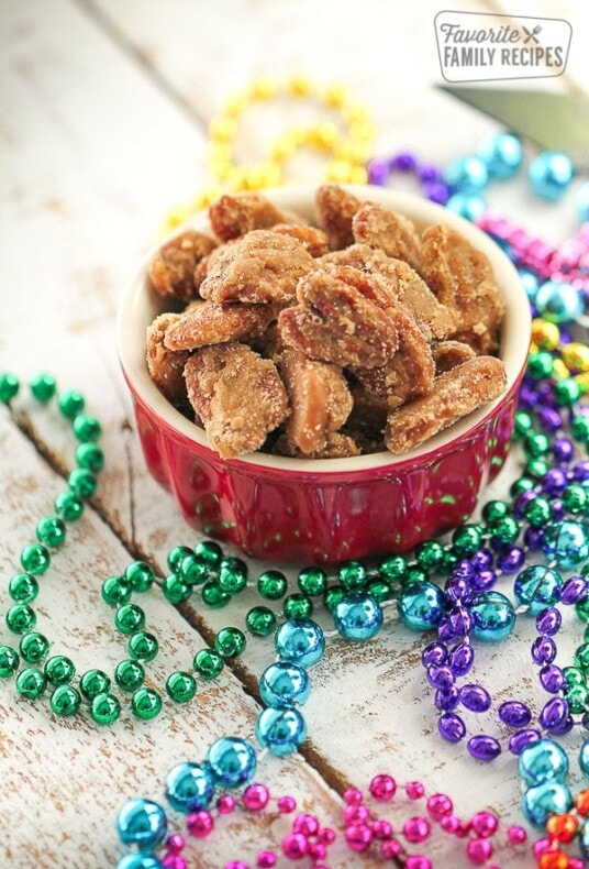 A bowl of pecan pralines with colorful Mardi Gras beads on the side