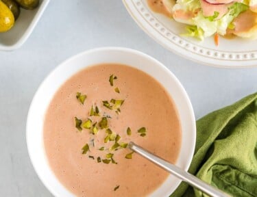 Russian dressing in a bowl topped with chopped pickles
