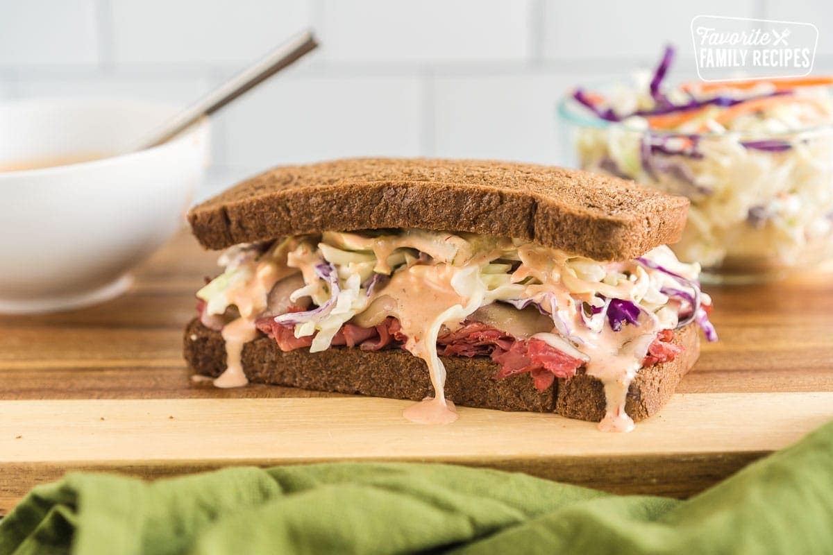 A corned beef sandwich on a cutting board with Russian Dressing dripping down the sides