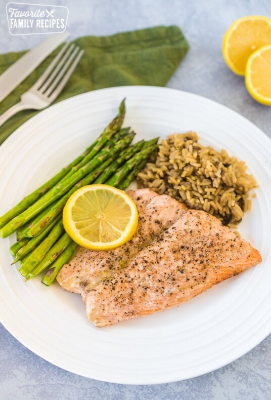 A large plate with asparagus, wild rice, and air fryer salmon topped with a lemon slice