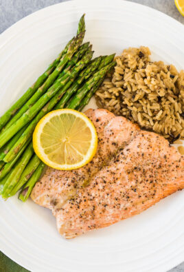 A large plate with asparagus, wild rice, and air fryer salmon topped with a lemon slice