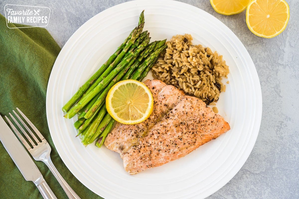 A large plate with asparagus, wild rice, and air fryer salmon topped with a lemon slice.