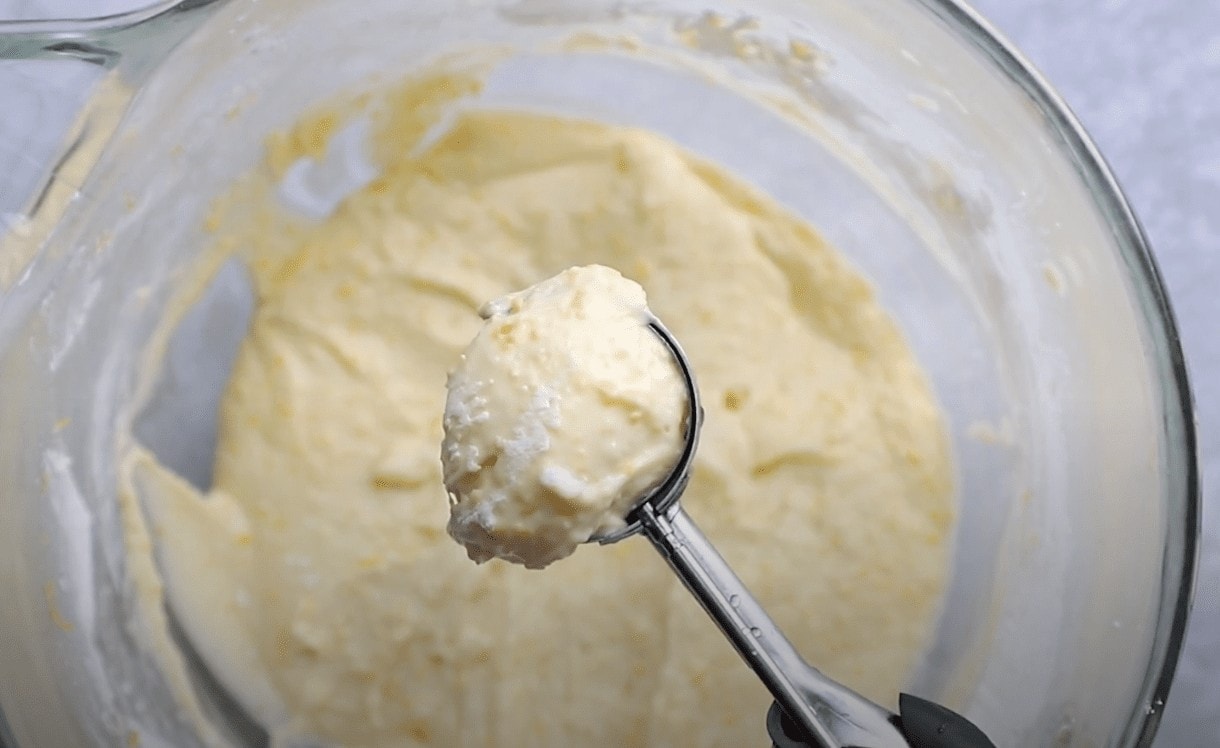 A cookie scoop scooping up Brazilian cheese bread dough