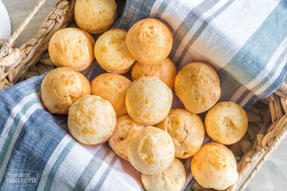 A bunch of Brazilian cheese bread rolls in a basket