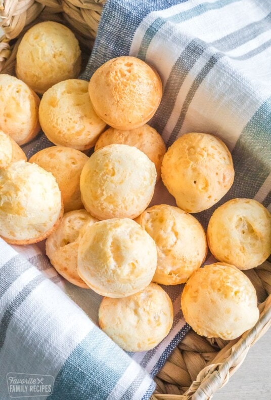 Brazilian cheese bread rolls in a basket, about a dozen small rolls.