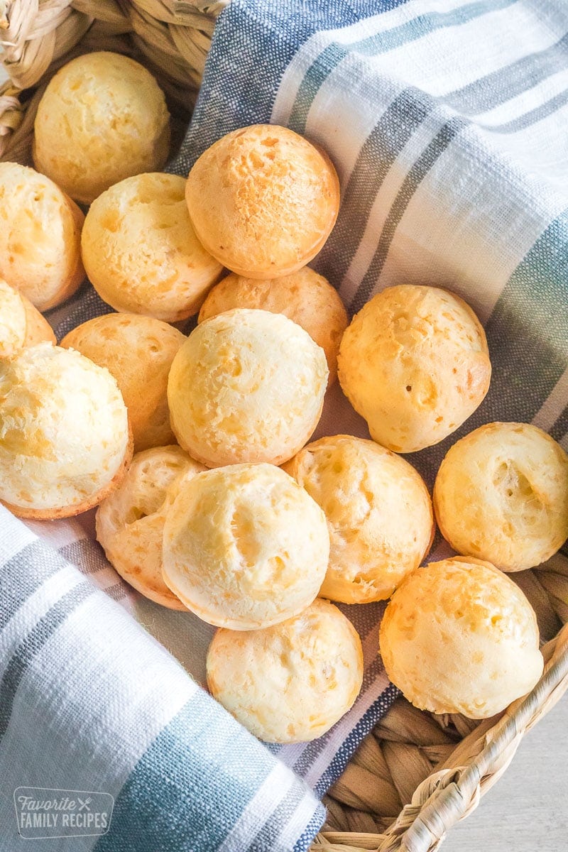 Brazilian cheese bread rolls in a basket, about a dozen small rolls.