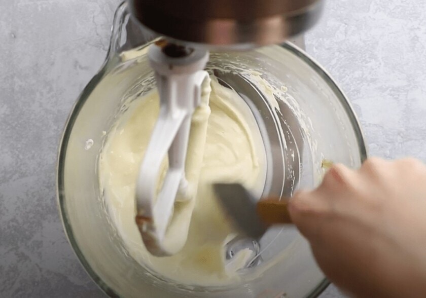 A mixing bowl with dough being scraped down