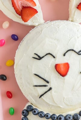 A bunny cake on pink baking sheet surrounded by jelly beans