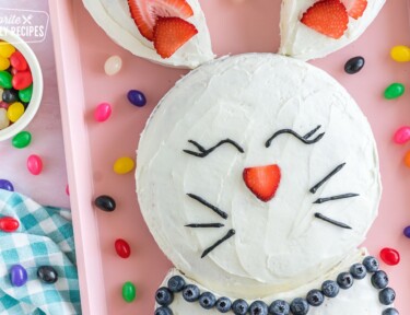 A bunny cake on pink baking sheet surrounded by jelly beans