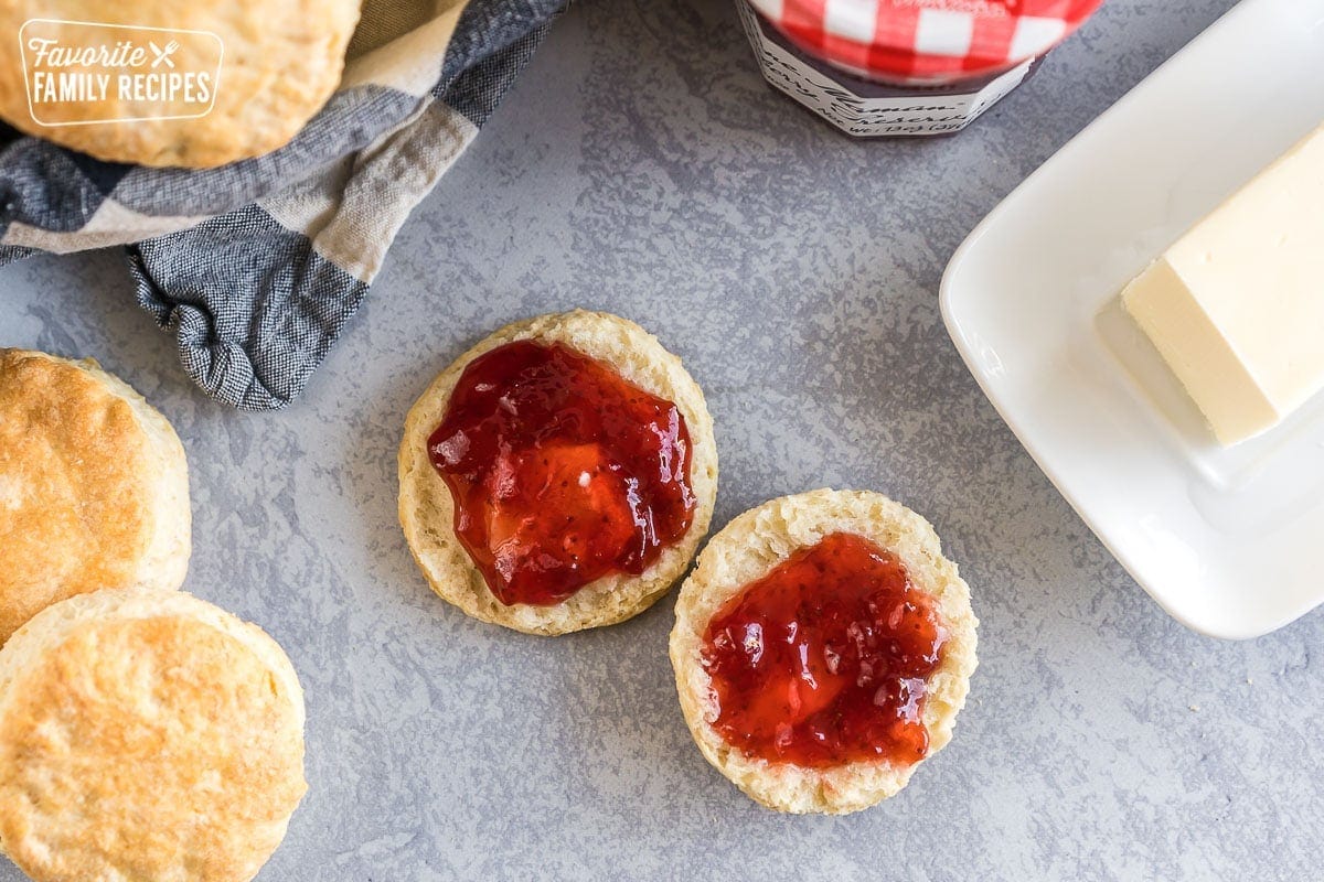 A buttermilk biscuit broken open with butter and jam spread on it