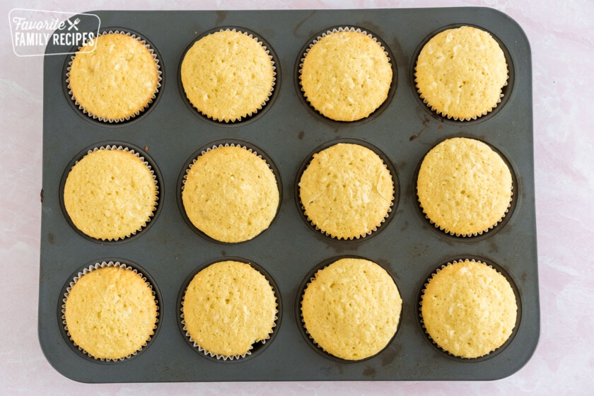 Baked but not frosted coconut cupcakes in a muffin pan