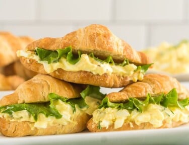 Three Egg Salad Sandwiches stacked on a white platter