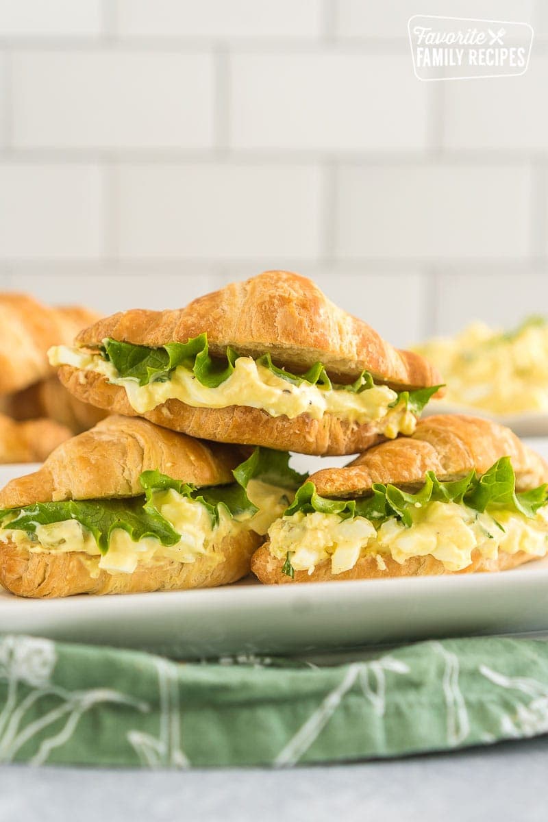 Three Egg Salad Sandwiches stacked on a white platter