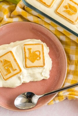 A scoop of banana pudding on a pink plate with two bananas in the background