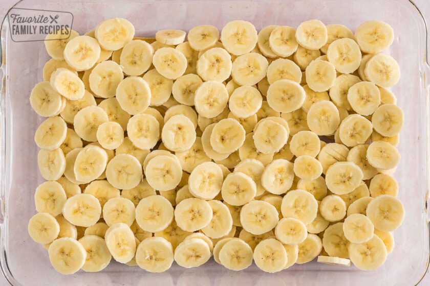 Chessman cookies and banana slices layered in the bottom of a baking dish