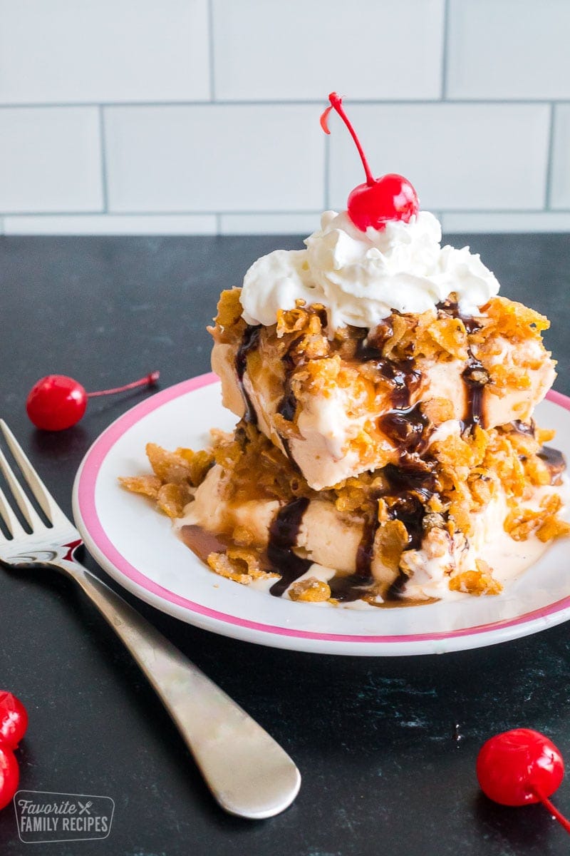 A place with a section of fried ice cream cake with whipped cream and a cherry on top