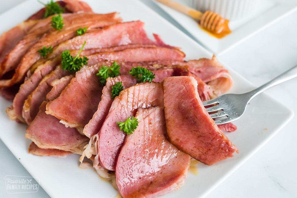 Slice honey baked ham being lifted by a fork