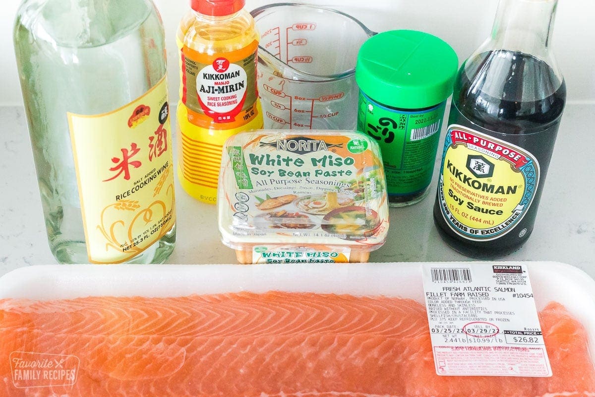 Ingredients to make Miso Salmon on a countertop including a salmon filet, white miso paste, Mirin, rice wine, soy sauce, and furikake seasoning.