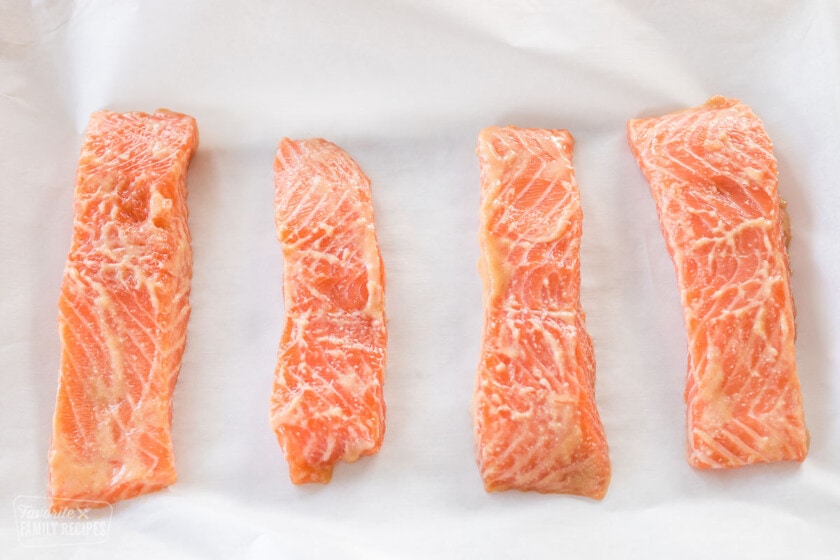 Four uncooked filets of salmon with a miso marinate over the top