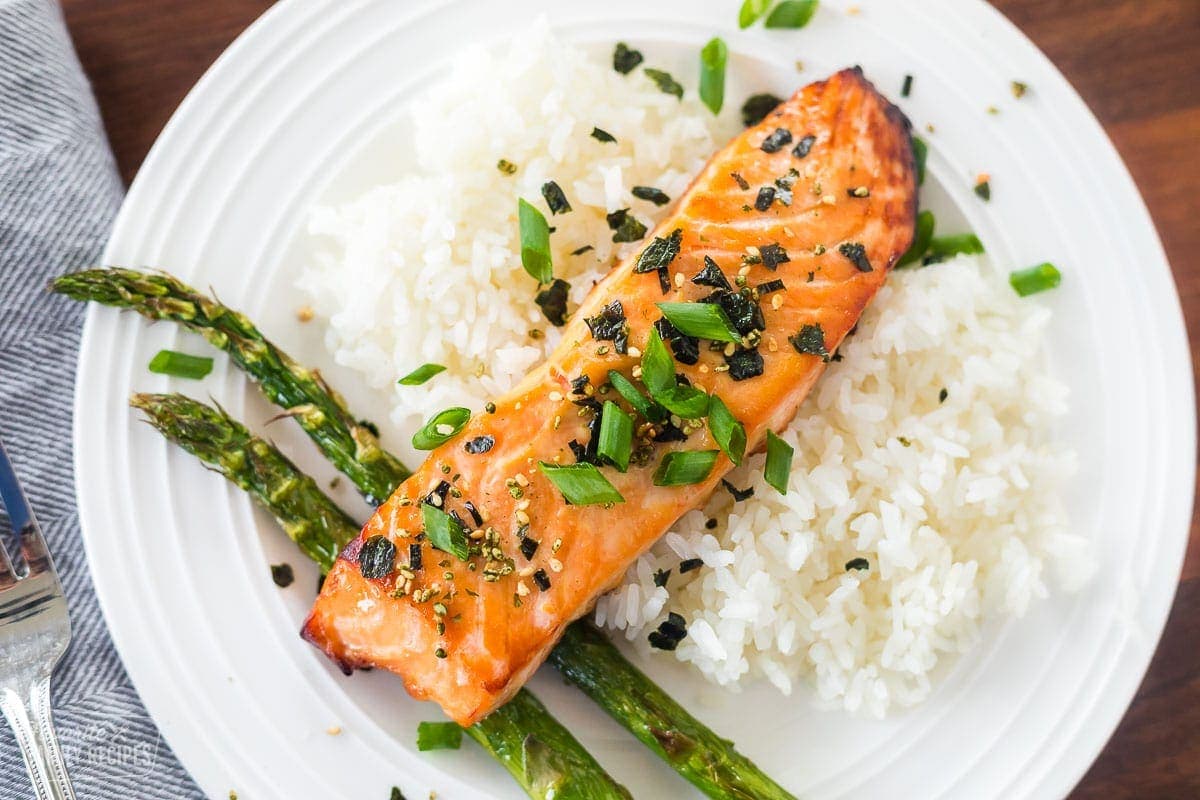 A top view of a plate of miso salmon, rice, and asparagus.