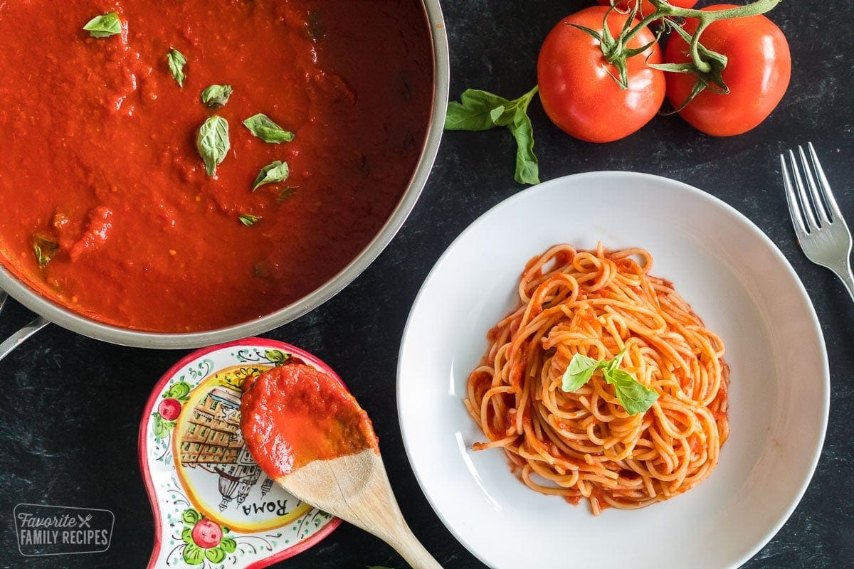 A plate of pasta al pomodoro (spaghetti with tomato sauce) next to a pan of fresh tomato sauce