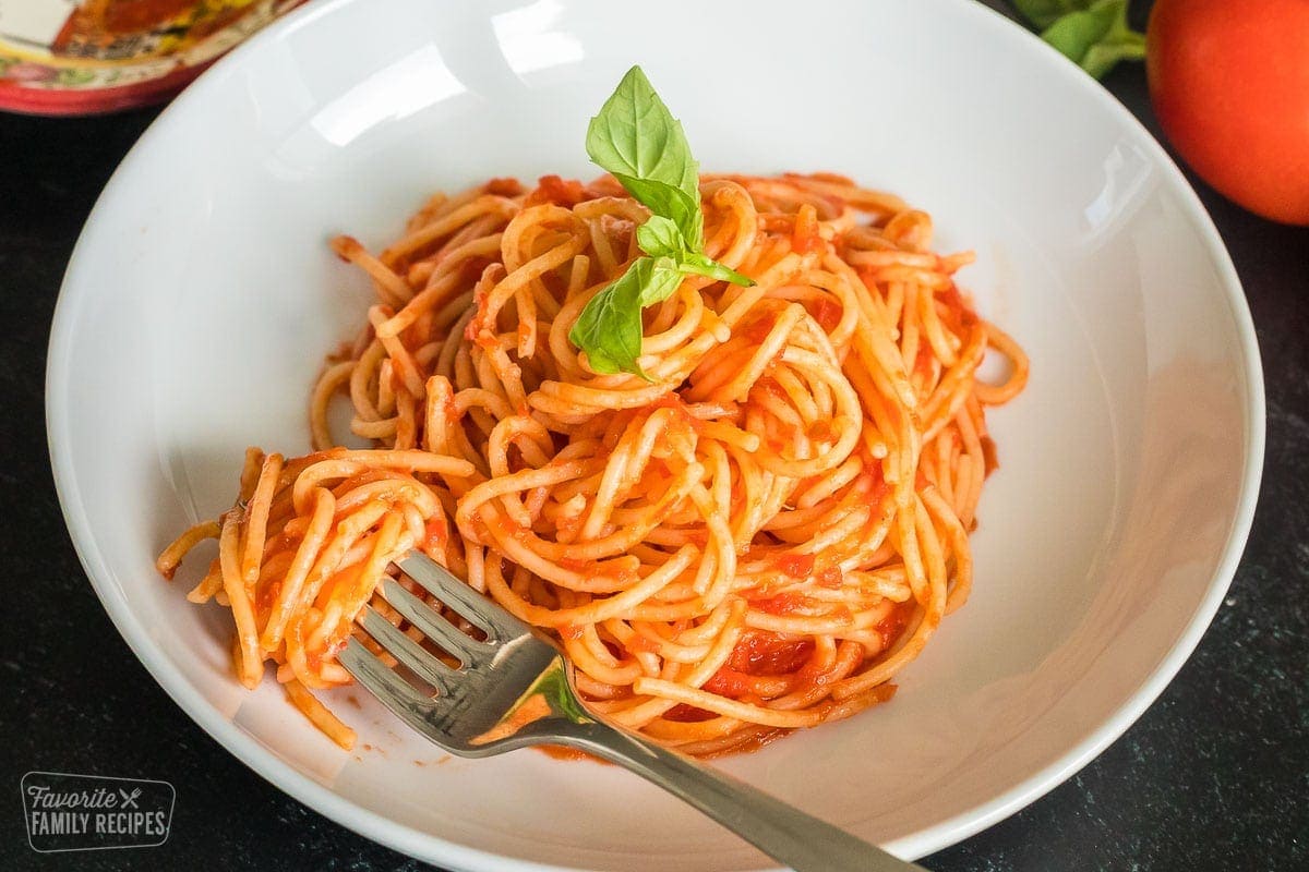 Spaghetti with pomodoro sauce in a shallow bowl with a fork twirling the pasta noodles