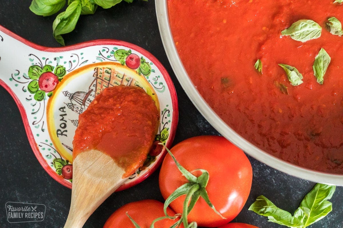 A close up of a wooden spoon covered in tomato sauce (pomodoro sauce)