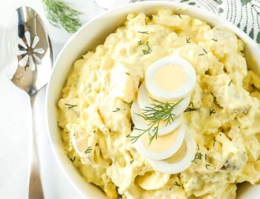 Top view of potato salad garnished with hard boiled egg and dill