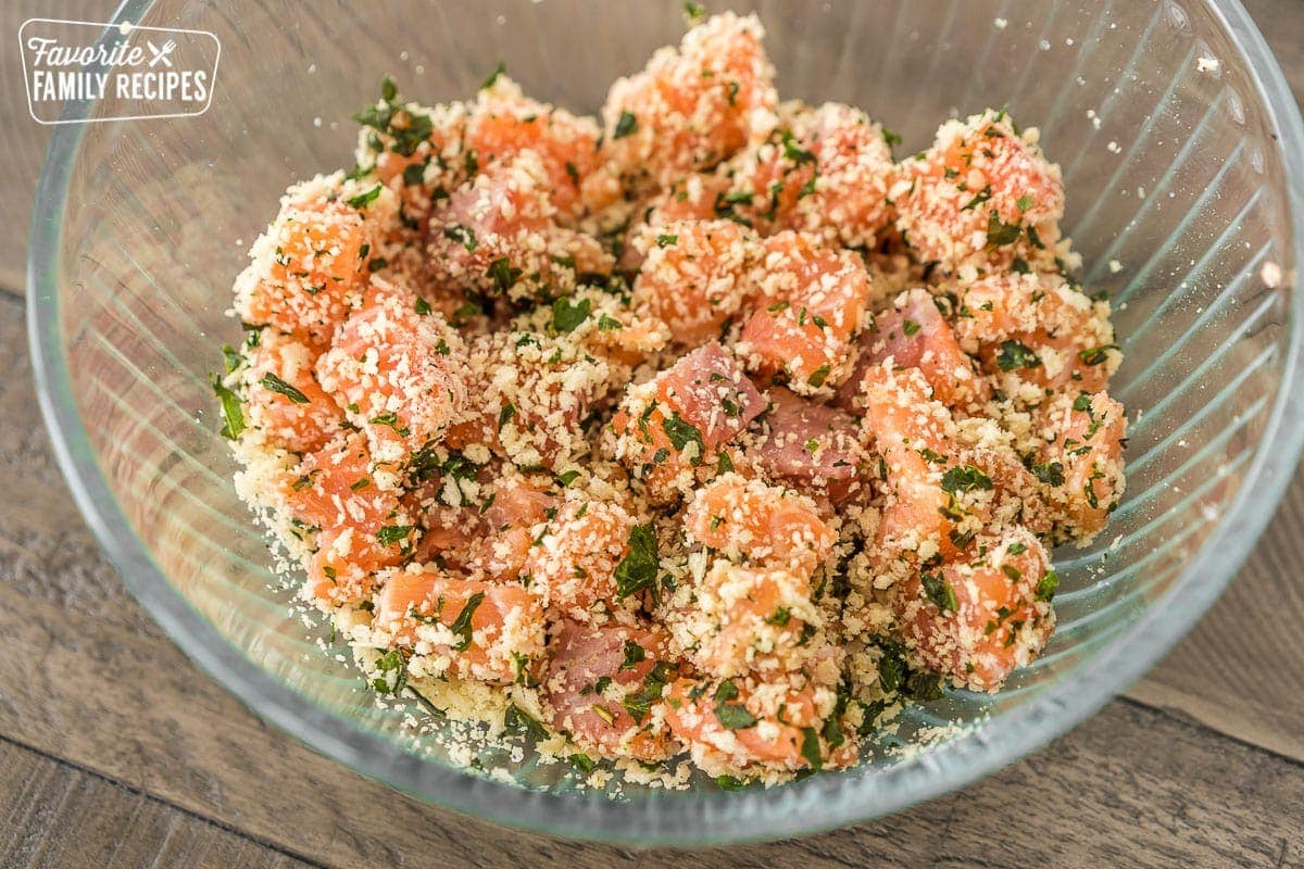 Raw salmon mixed with basil and breadcrumbs in a bowl