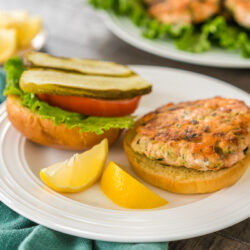 A salmon patty on a burger with salmon patties in the background