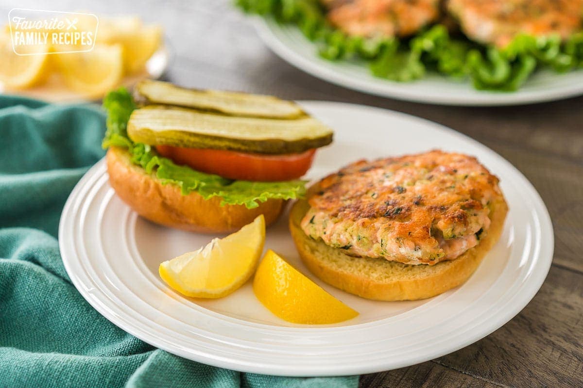 A salmon patty on a burger with salmon patties in the background