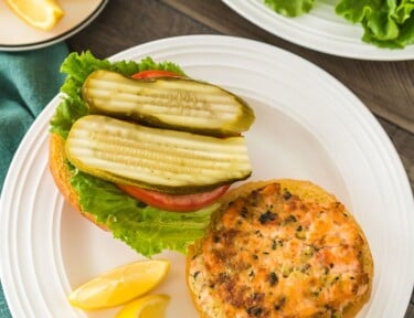 A plate of salmon patties and another plate with an open-faced salmon burger