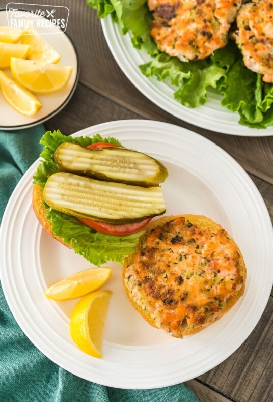 A plate of salmon patties and another plate with an open-faced salmon burger
