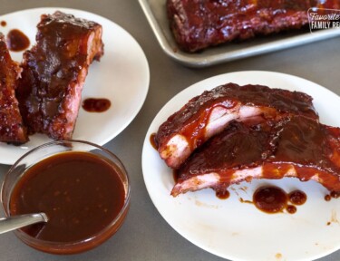 smoked ribs on two plates with a side of bbq sauce