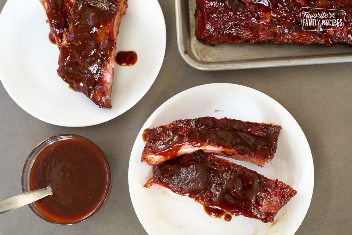 sections of smoked ribs on two plates with a side of bbq sauce