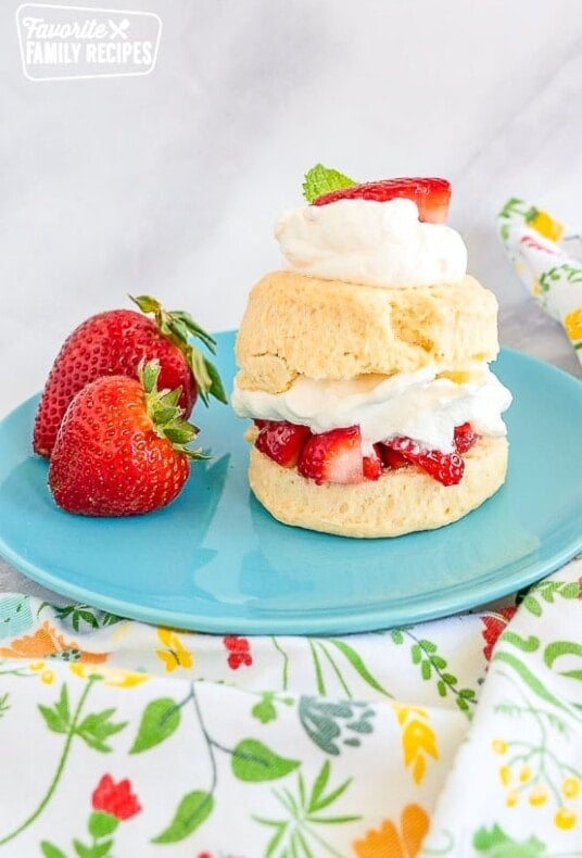 Strawberry shortcake and strawberries on a blue plate on top of a marble countertop