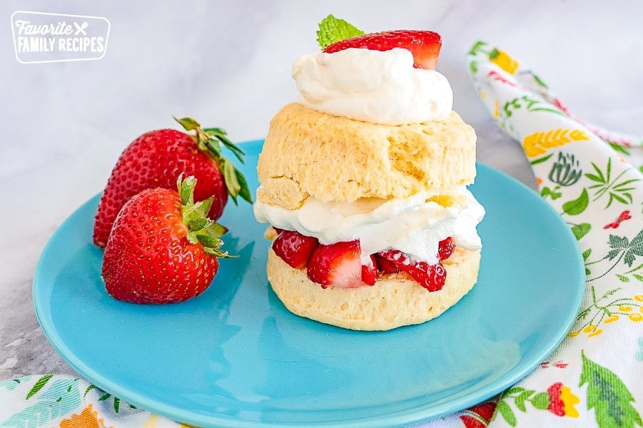 Strawberry shortcake on a blue plate on top of a marble countertop.