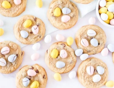 Table with multiple Cadbury egg cookies with a bowl of mini Cadbury egg candies