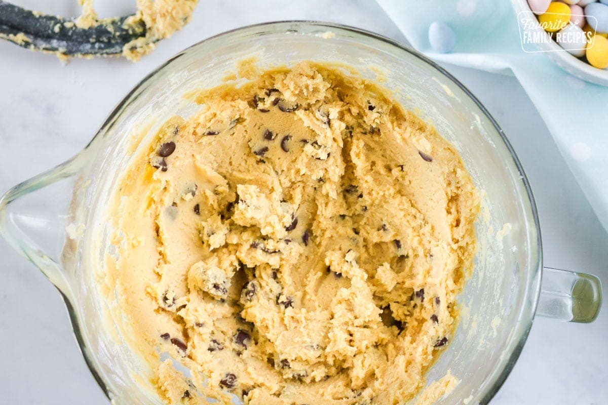 Large mixing bowl of cookie dough with chocolate chips to make Cadbury cookies.