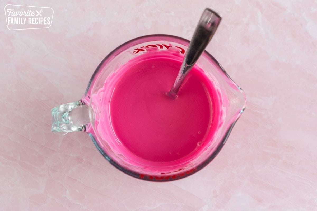 Pink candy melts melted in a glass measuring cup